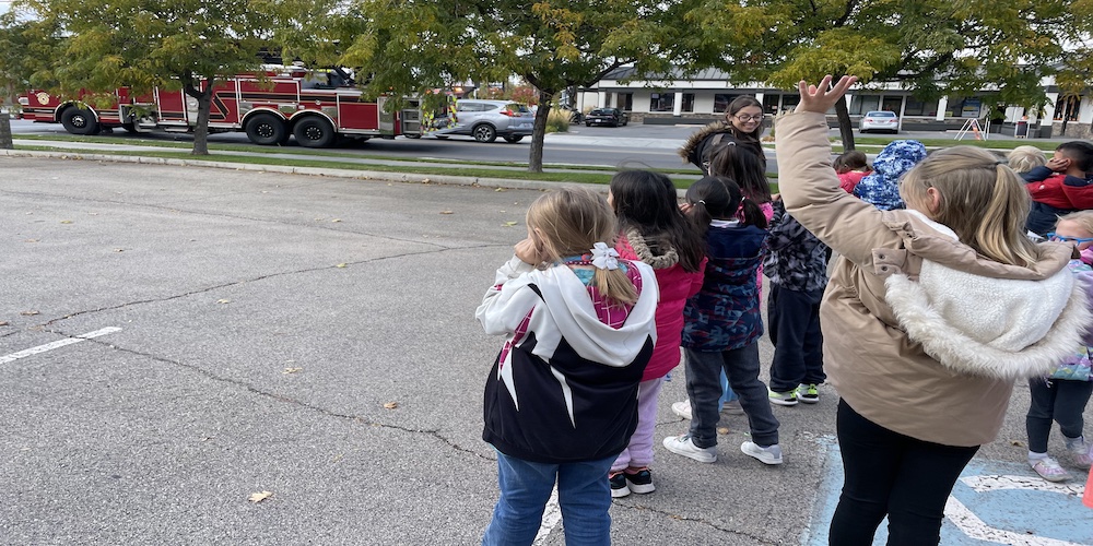 2 graders waving to a fire truck outside