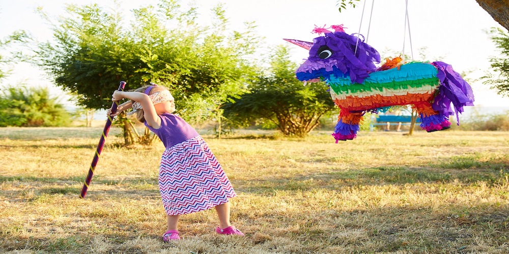 photo of a little girl with a blindfold on hitting a pinata with a stick