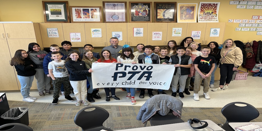 students surrounding the teacher with a PTA banner in front